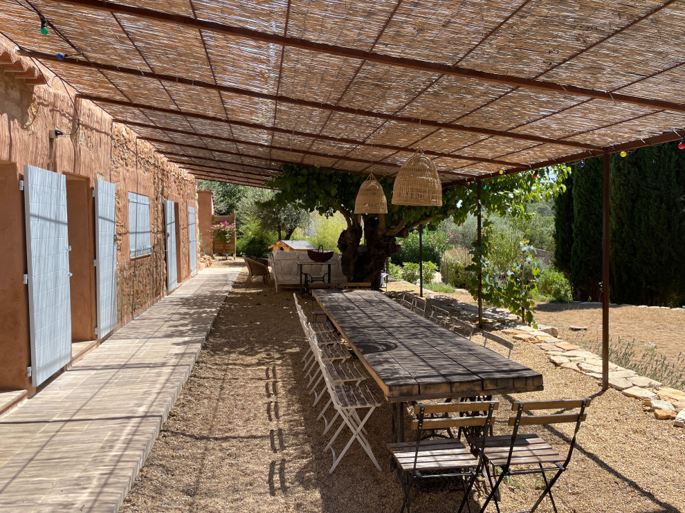 Farmhouse patio in Other with gravel and a pergola.