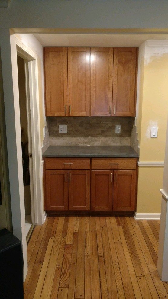 Example of a minimalist kitchen design in New York with an undermount sink, shaker cabinets, solid surface countertops, beige backsplash, ceramic backsplash, stainless steel appliances, an island and gray countertops