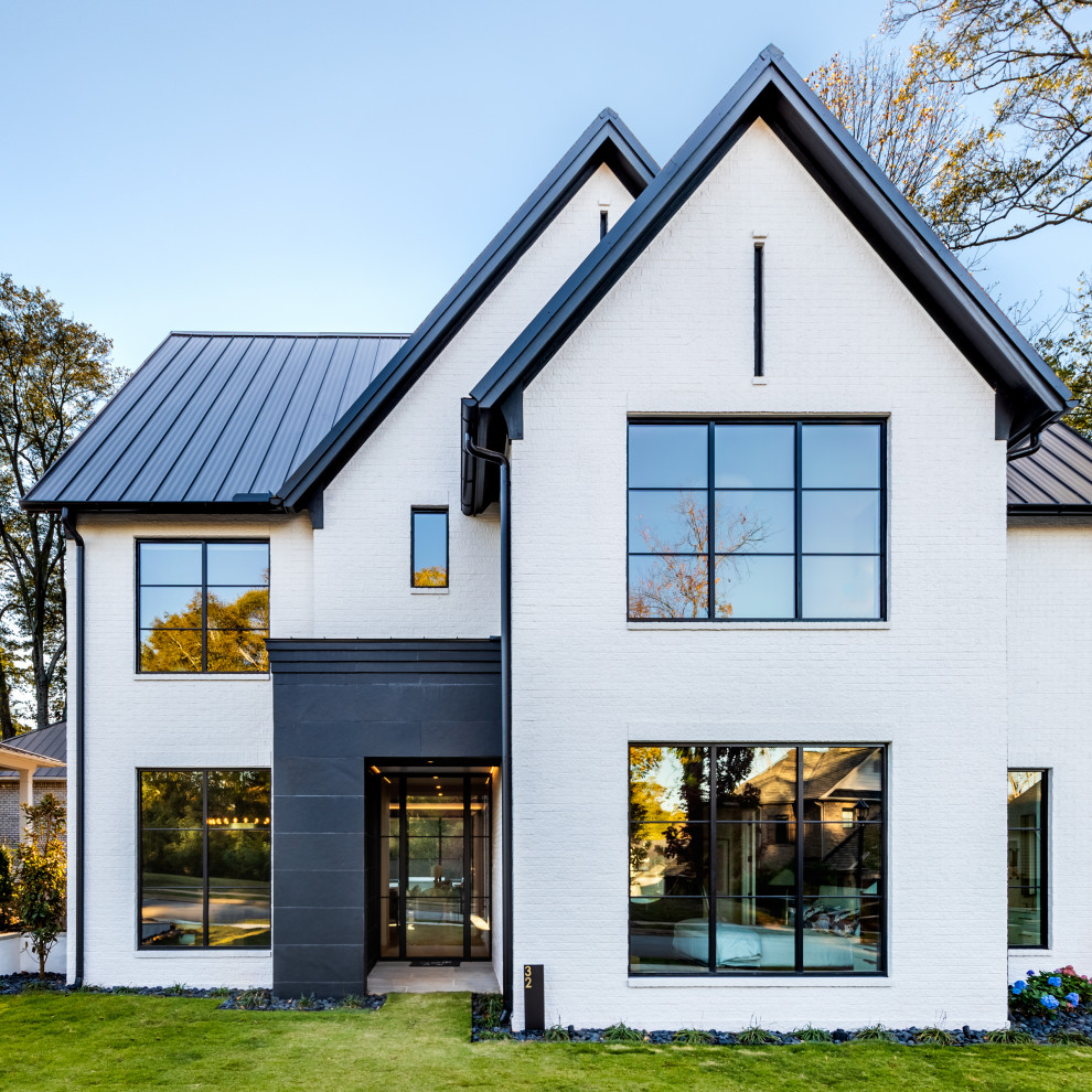 Exemple d'une façade de maison blanche tendance en brique à un étage avec un toit à deux pans, un toit en métal et un toit noir.