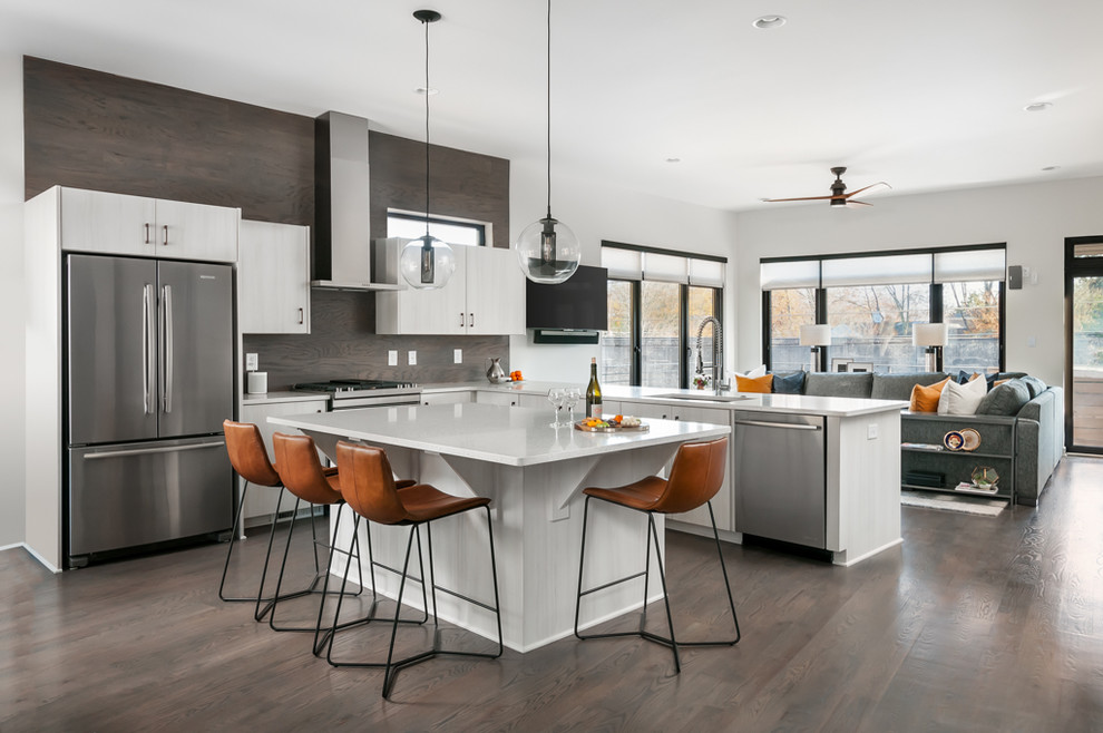 Large contemporary l-shaped open plan kitchen in Atlanta with brown floor, an undermount sink, flat-panel cabinets, beige cabinets, brown splashback, timber splashback, stainless steel appliances, dark hardwood floors, with island, solid surface benchtops and white benchtop.