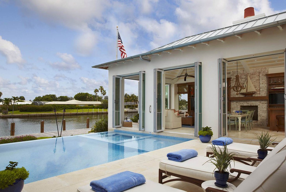 Inspiration for an expansive tropical backyard custom-shaped infinity pool in Miami with tile and a hot tub.