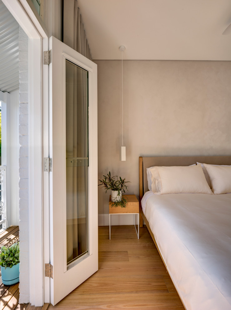 Inspiration for a small contemporary master bedroom in Sydney with beige walls, light hardwood floors and brown floor.