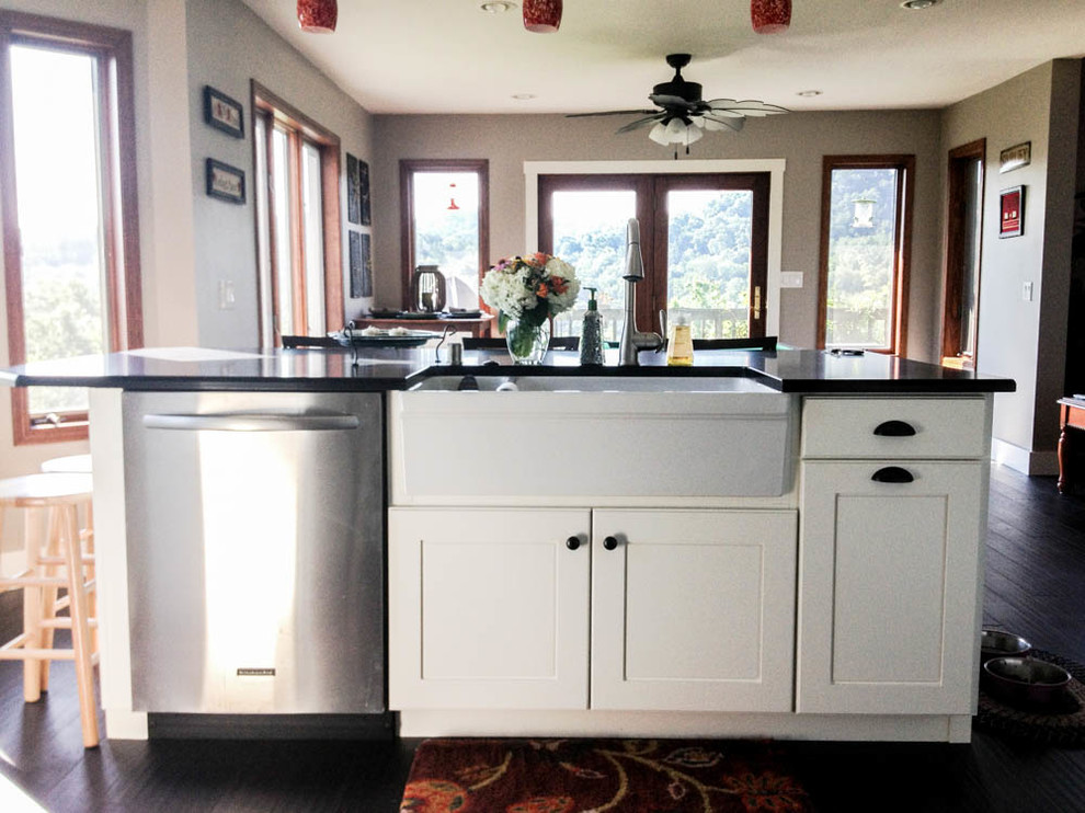 Large transitional l-shaped open concept kitchen photo with a farmhouse sink, shaker cabinets, white cabinets, quartz countertops, stainless steel appliances and an island