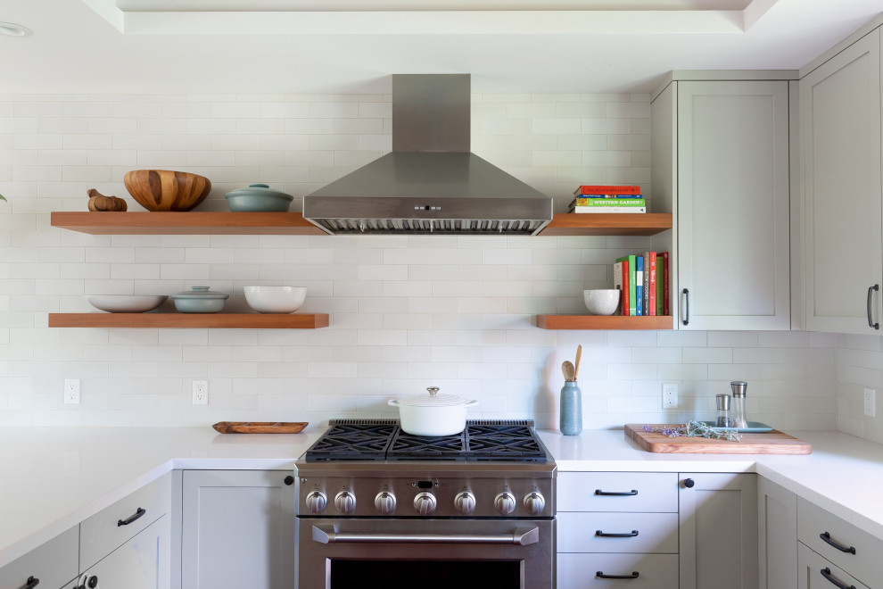 Mid-sized transitional u-shaped light wood floor and brown floor open concept kitchen photo with a farmhouse sink, shaker cabinets, gray cabinets, quartz countertops, white backsplash, ceramic backsplash, stainless steel appliances, a peninsula and white countertops