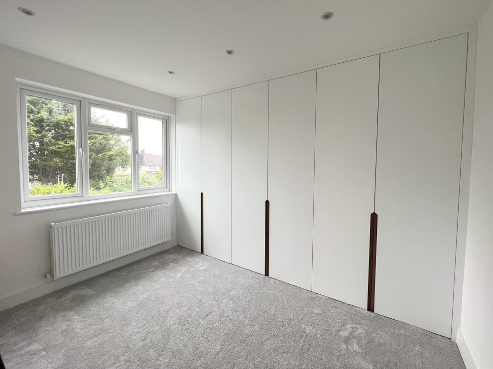 Mittelgroßes Modernes Gästezimmer ohne Kamin mit weißer Wandfarbe, Teppichboden und grauem Boden in London