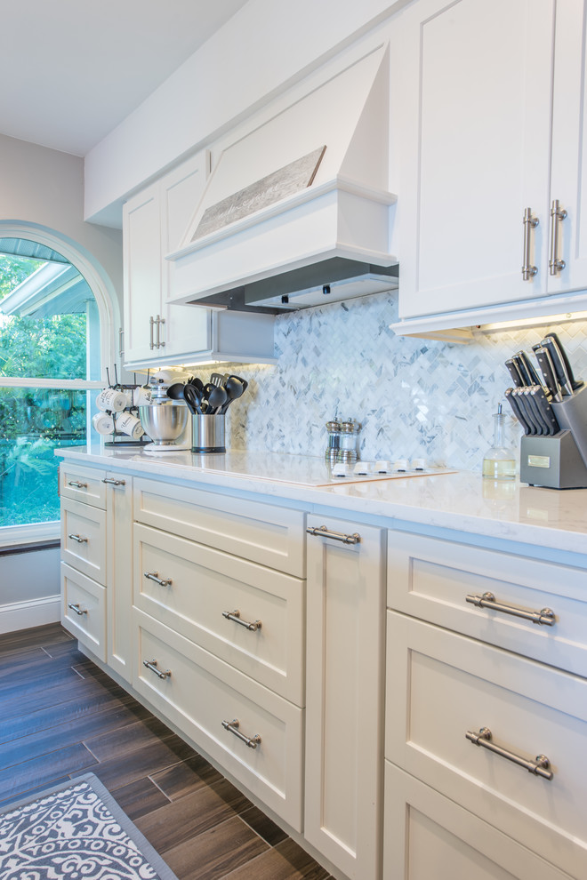 Inspiration for a large transitional u-shaped porcelain tile and brown floor eat-in kitchen remodel with an undermount sink, shaker cabinets, white cabinets, quartz countertops, white backsplash, marble backsplash, stainless steel appliances and two islands