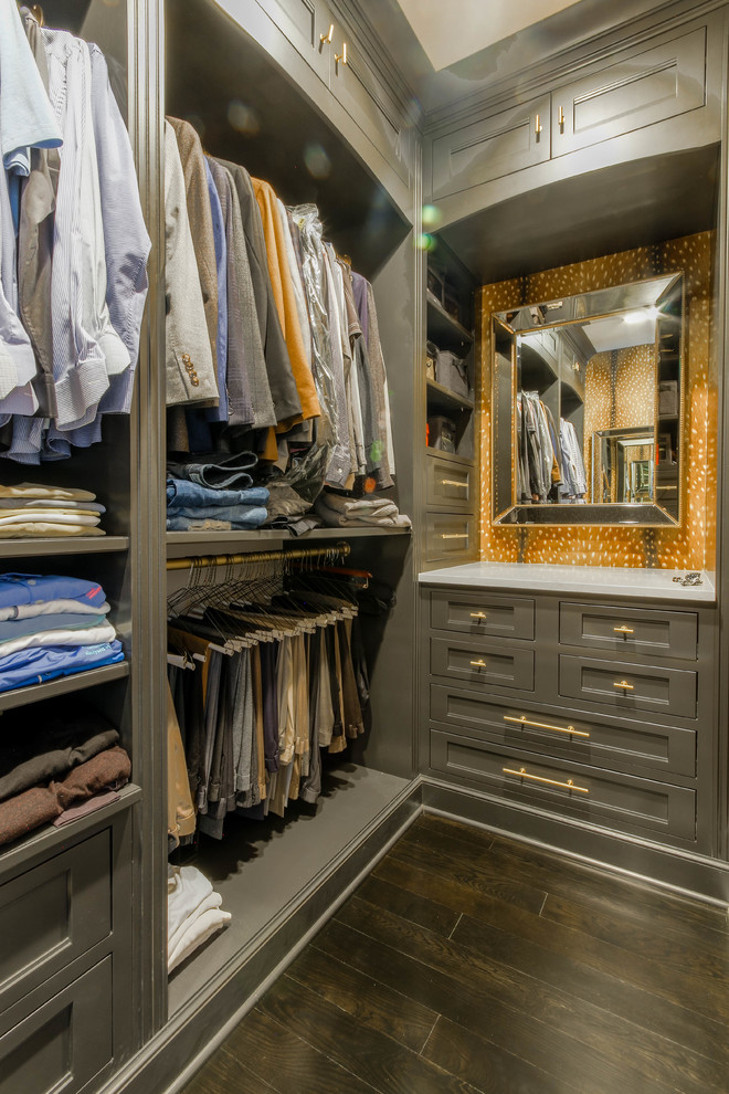 This is an example of a mid-sized traditional men's walk-in wardrobe in Detroit with recessed-panel cabinets, grey cabinets, dark hardwood floors and brown floor.