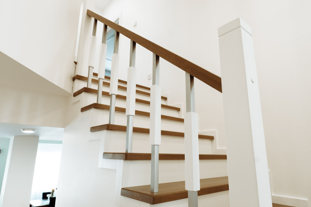 На фото: большая изогнутая деревянная лестница в современном стиле с деревянными ступенями, металлическими перилами и кирпичными стенами