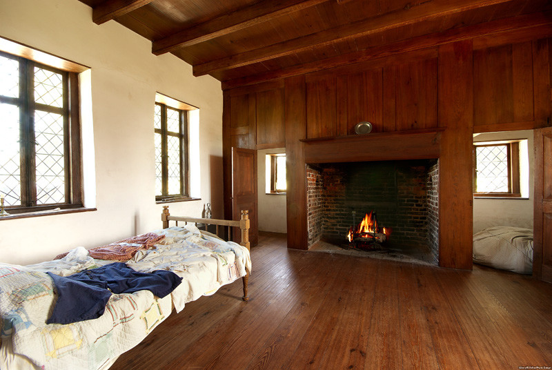 Photo of a mid-sized traditional guest bedroom in New York with white walls, dark hardwood floors, a standard fireplace and a wood fireplace surround.
