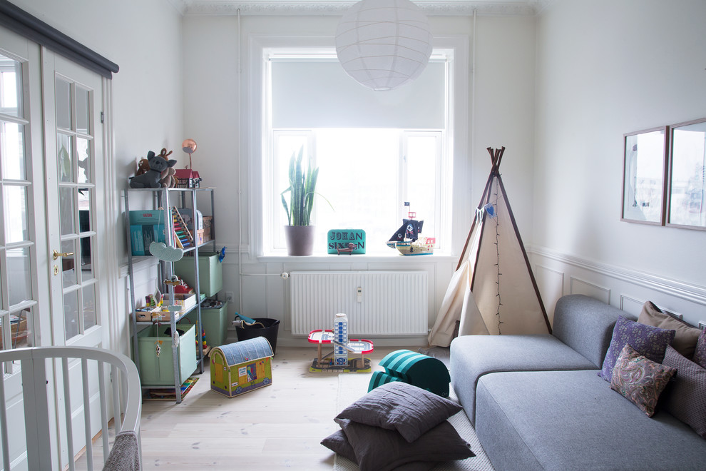 Photo of a mid-sized scandinavian gender-neutral kids' room in Copenhagen with white walls and light hardwood floors.