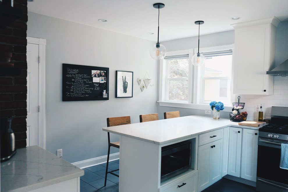 This is an example of a mid-sized modern u-shaped separate kitchen in Philadelphia with a farmhouse sink, shaker cabinets, white cabinets, quartz benchtops, white splashback, subway tile splashback, stainless steel appliances, porcelain floors, a peninsula, black floor and white benchtop.