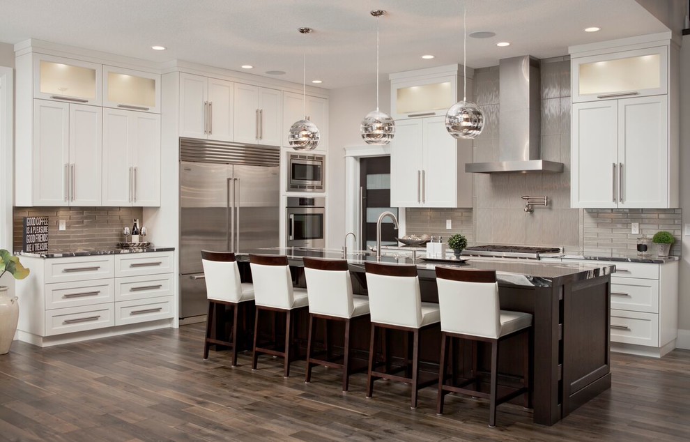 This is an example of a large transitional single-wall eat-in kitchen in Toronto with shaker cabinets, white cabinets, marble benchtops, metallic splashback, metal splashback, stainless steel appliances, dark hardwood floors, with island and brown floor.