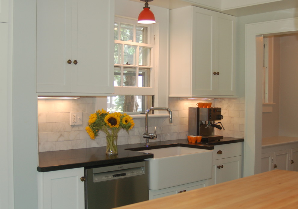 Mid-sized traditional l-shaped separate kitchen in New York with a farmhouse sink, recessed-panel cabinets, white cabinets, granite benchtops, white splashback, subway tile splashback, stainless steel appliances and with island.