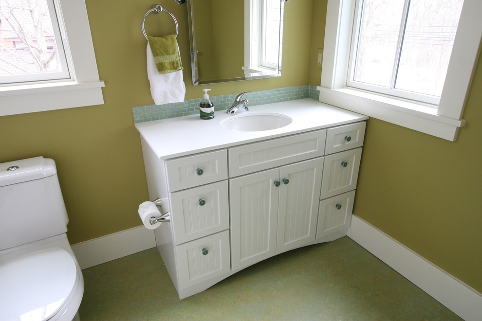 Inspiration for a mid-sized traditional 3/4 bathroom in Detroit with white cabinets, a two-piece toilet, blue tile, porcelain tile, green walls, an undermount sink and solid surface benchtops.