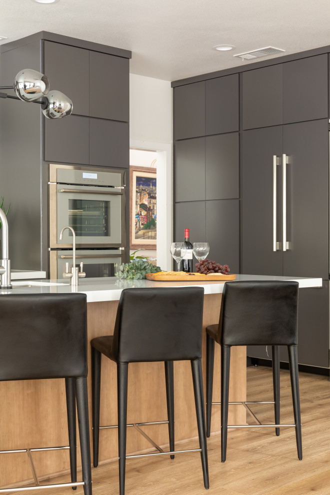 Esempio di una cucina moderna di medie dimensioni con ante lisce, ante grigie, top in quarzo composito, elettrodomestici in acciaio inossidabile, pavimento in legno massello medio e top bianco