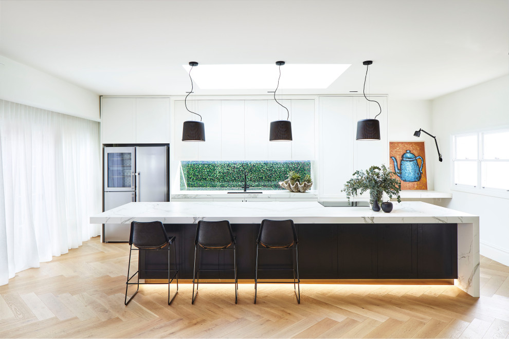 This is an example of an expansive contemporary kitchen in Sydney with shaker cabinets, white cabinets, quartz benchtops, window splashback, stainless steel appliances, with island, a single-bowl sink, light hardwood floors, beige floor and white benchtop.