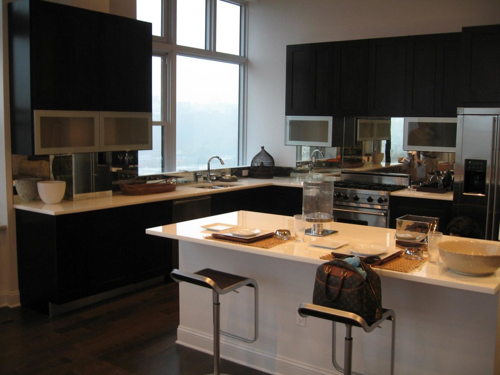 This is an example of a modern l-shaped eat-in kitchen in New York with a double-bowl sink, flat-panel cabinets, white cabinets, solid surface benchtops, stainless steel appliances, medium hardwood floors and with island.