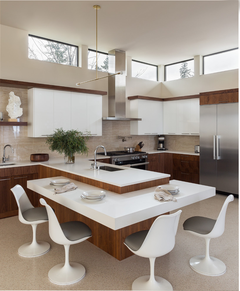 Photo of a contemporary u-shaped eat-in kitchen in Seattle with an undermount sink, flat-panel cabinets, medium wood cabinets, beige splashback, stainless steel appliances, a peninsula, beige floor and white benchtop.