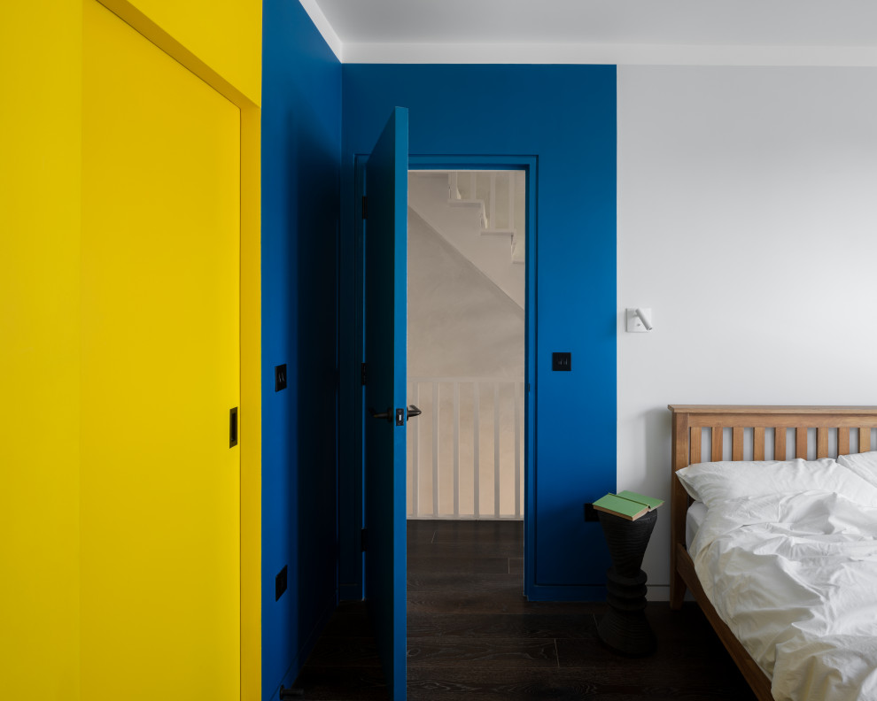 Cette photo montre une chambre d'amis tendance avec un mur bleu, parquet foncé et un sol marron.