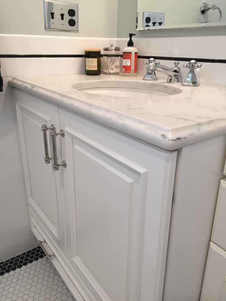 Photo of a mid-sized traditional 3/4 bathroom in Newark with raised-panel cabinets, white cabinets, an alcove tub, a shower/bathtub combo, a two-piece toilet, white tile, porcelain tile, green walls, mosaic tile floors, an undermount sink, engineered quartz benchtops, white floor and a shower curtain.