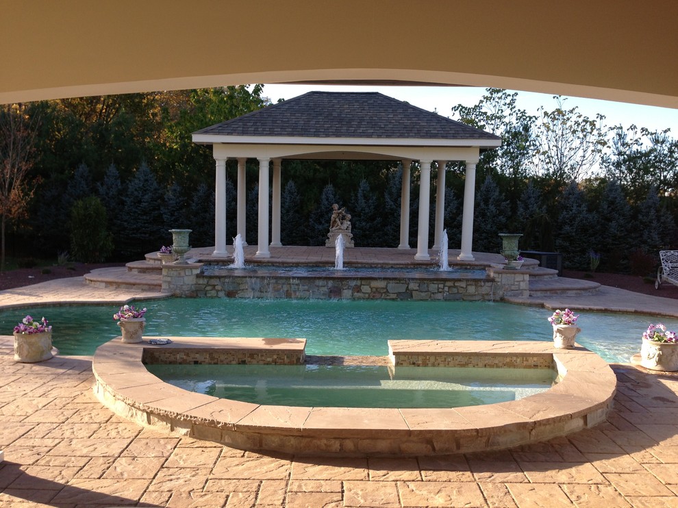 Photo of a large traditional backyard custom-shaped pool in Philadelphia with a water feature and concrete pavers.