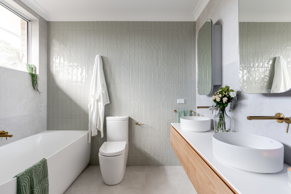 Design ideas for a large modern kids bathroom in Sydney with flat-panel cabinets, medium wood cabinets, a corner shower, a two-piece toilet, white tile, green walls, a vessel sink, grey floor, a hinged shower door, white benchtops, a double vanity and a floating vanity.