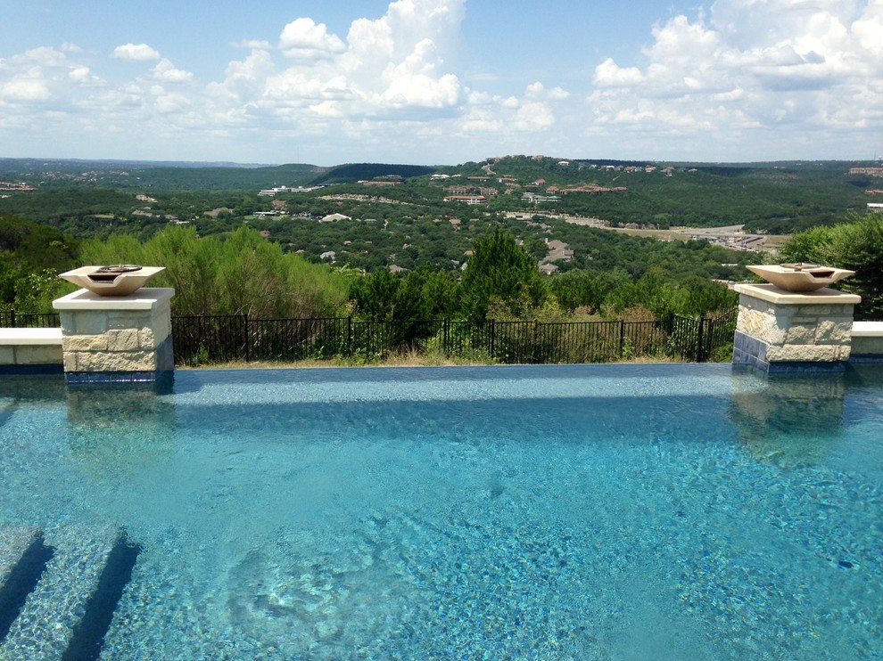 Photo of a contemporary backyard rectangular infinity pool in Austin with a water feature and stamped concrete.