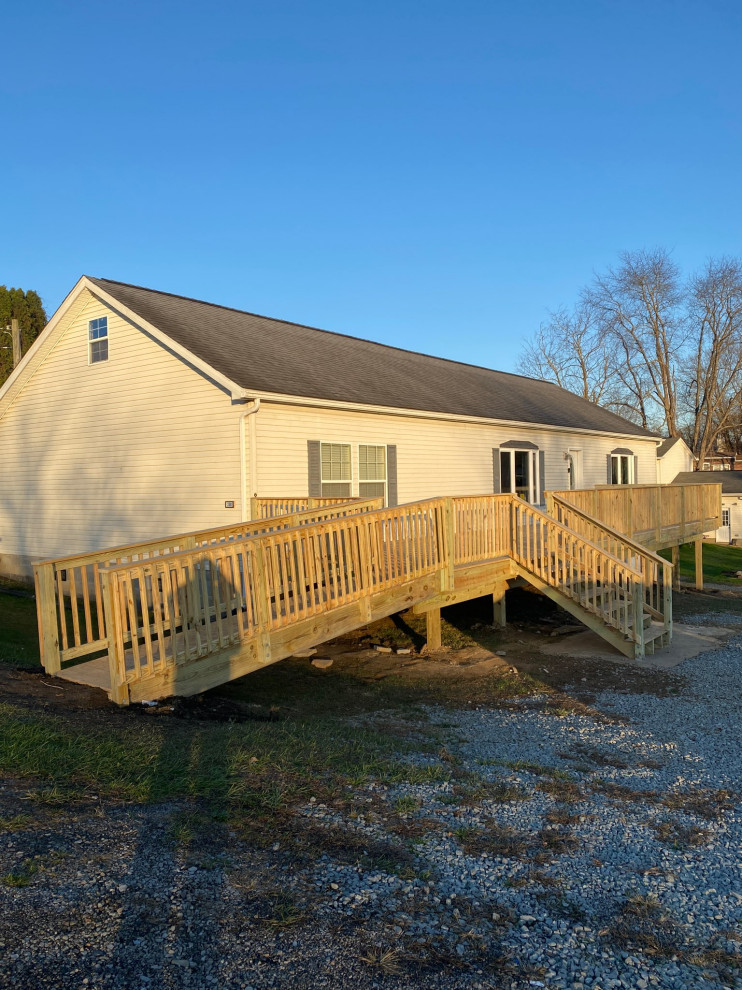 Example of a mid-sized mountain style backyard ground level wood railing deck design with no cover