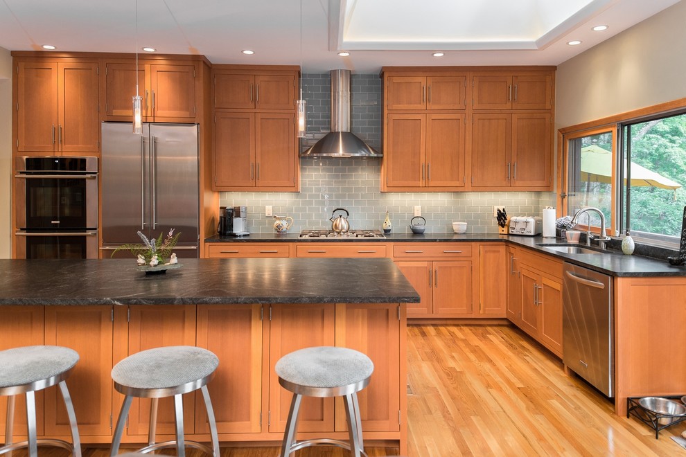 Inspiration for a contemporary l-shaped kitchen in New York with an undermount sink, shaker cabinets, light wood cabinets, granite benchtops, grey splashback, glass tile splashback, stainless steel appliances, with island and medium hardwood floors.