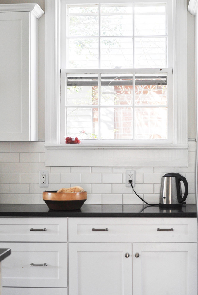 Inspiration for a mid-sized transitional l-shaped medium tone wood floor home design remodel in Richmond with a farmhouse sink, shaker cabinets, white cabinets, granite countertops, white backsplash, subway tile backsplash and stainless steel appliances