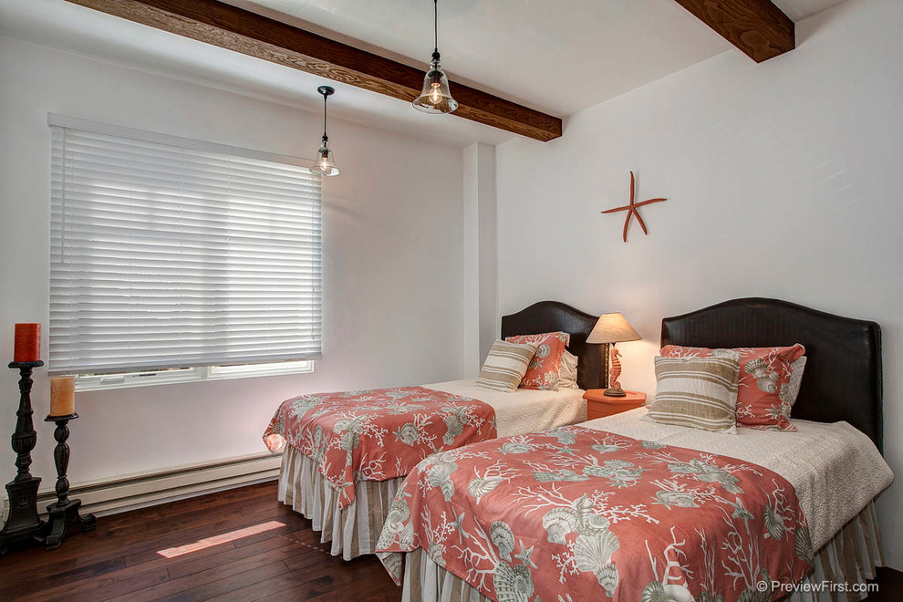 This is an example of a large mediterranean guest bedroom in San Diego with white walls and dark hardwood floors.