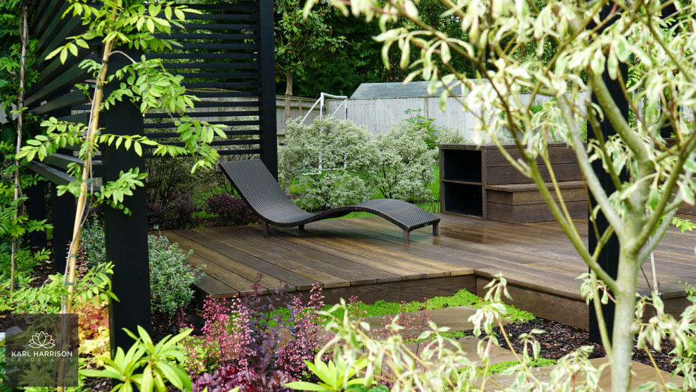 Foto di un grande giardino moderno esposto in pieno sole dietro casa in estate con pedane e recinzione in legno