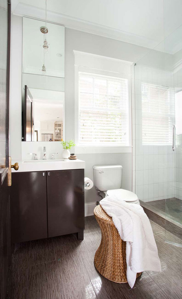 This is an example of a mid-sized contemporary 3/4 bathroom in Atlanta with flat-panel cabinets, dark wood cabinets, an alcove shower, an undermount sink, solid surface benchtops, a two-piece toilet, brown tile, grey walls and brown floor.