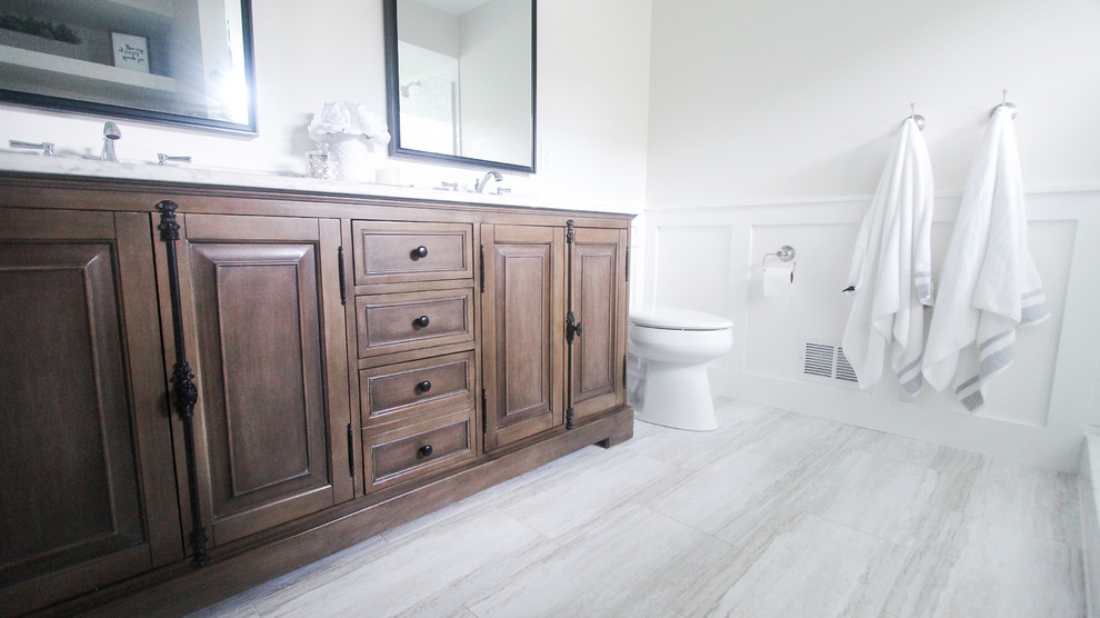 Mid-sized country master bathroom in Minneapolis with brown cabinets, a double shower, a two-piece toilet, white tile, subway tile, white walls, vinyl floors, an undermount sink, marble benchtops, grey floor, a hinged shower door and white benchtops.