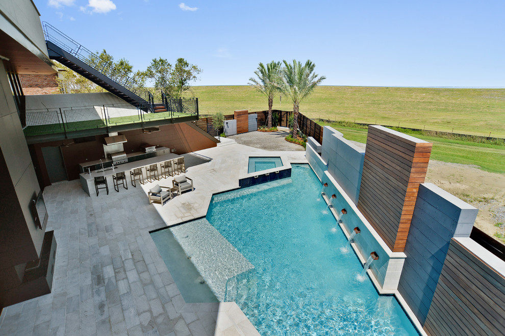 Photo of a large modern backyard custom-shaped pool in New Orleans with a water feature and concrete pavers.