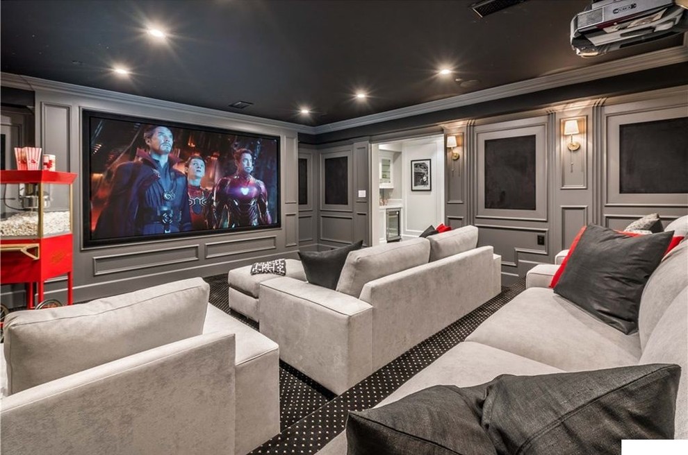 This is an example of a large transitional enclosed home theatre in Los Angeles with grey walls, carpet, a projector screen and black floor.