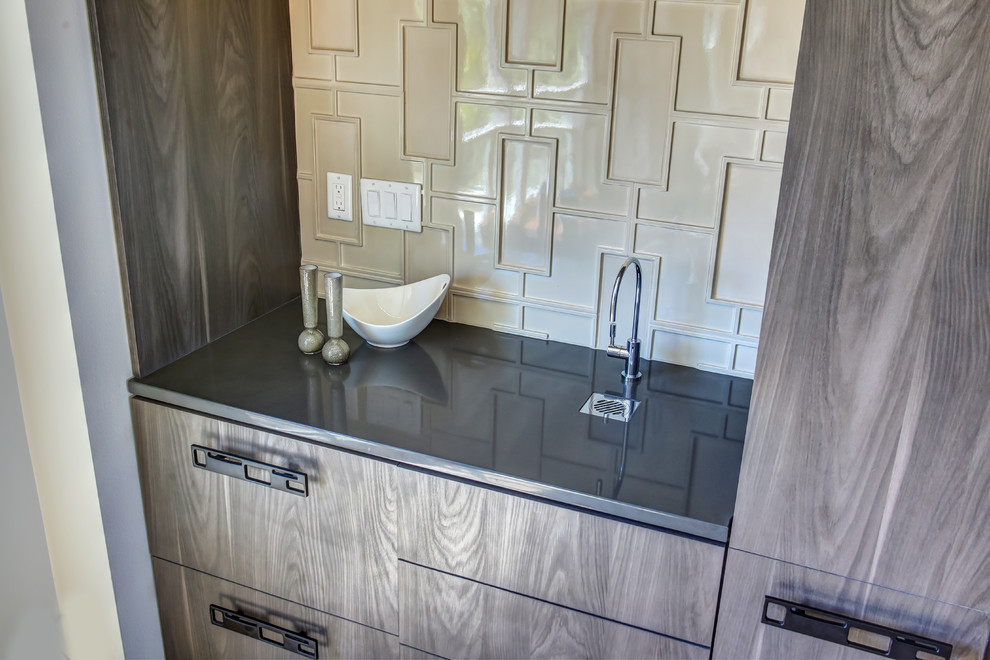 Photo of a small modern single-wall wet bar in Miami with an integrated sink, flat-panel cabinets, grey cabinets, quartz benchtops, grey splashback and light hardwood floors.