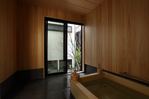 This is an example of a small asian master bathroom in Kyoto with beaded inset cabinets, light wood cabinets, a hot tub, an open shower, a one-piece toilet, gray tile, stone tile, grey walls, porcelain floors, an undermount sink, solid surface benchtops, grey floor, an open shower and white benchtops.