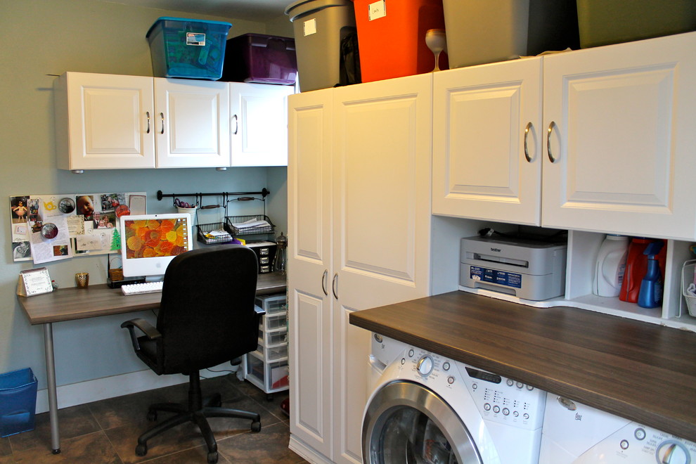 Photo of a traditional utility room in Denver with raised-panel cabinets, laminate benchtops, blue walls, ceramic floors and a side-by-side washer and dryer.