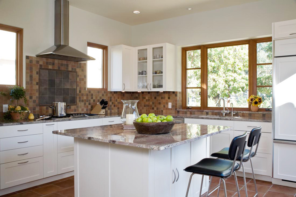 Contemporary l-shaped kitchen in San Francisco with shaker cabinets, an undermount sink, white cabinets, brown splashback, stone tile splashback, panelled appliances and terra-cotta floors.