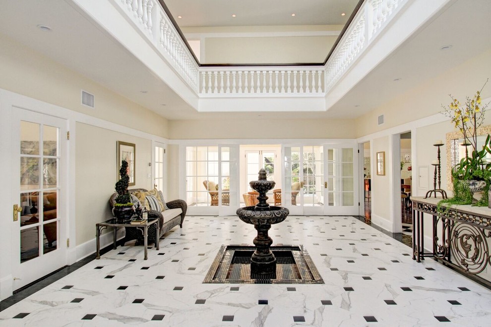 Traditional entryway in Los Angeles with beige walls and marble floors.