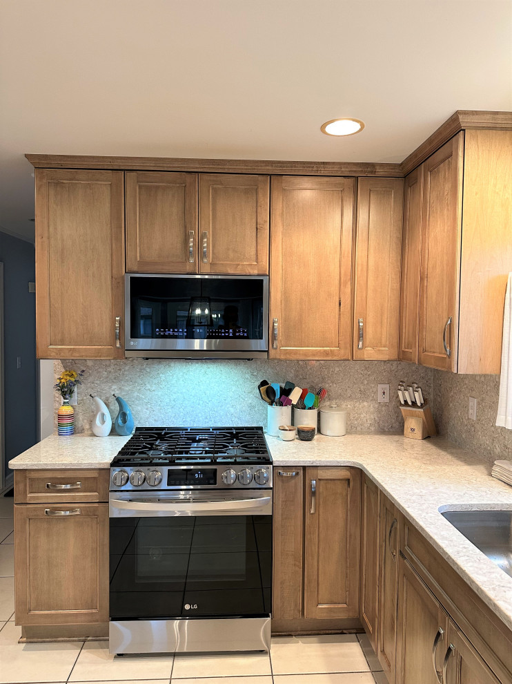 Design ideas for a mid-sized traditional u-shaped eat-in kitchen in Detroit with an undermount sink, shaker cabinets, medium wood cabinets, quartz benchtops, beige splashback, engineered quartz splashback, stainless steel appliances and a peninsula.