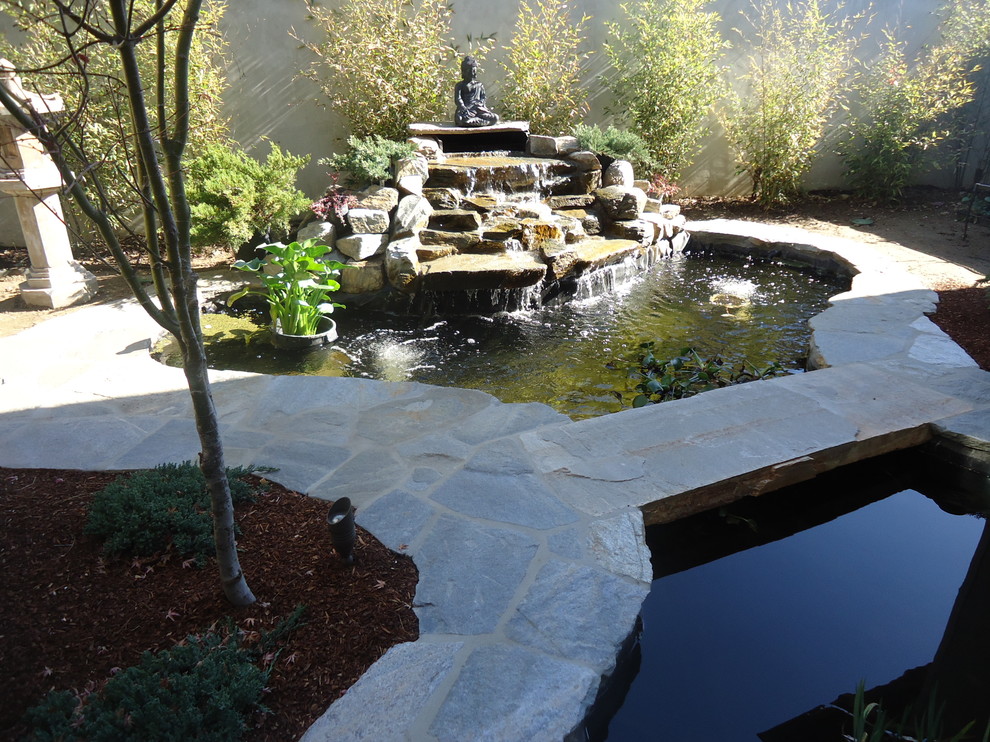 Photo of an eclectic side yard garden in Los Angeles with a water feature and natural stone pavers.