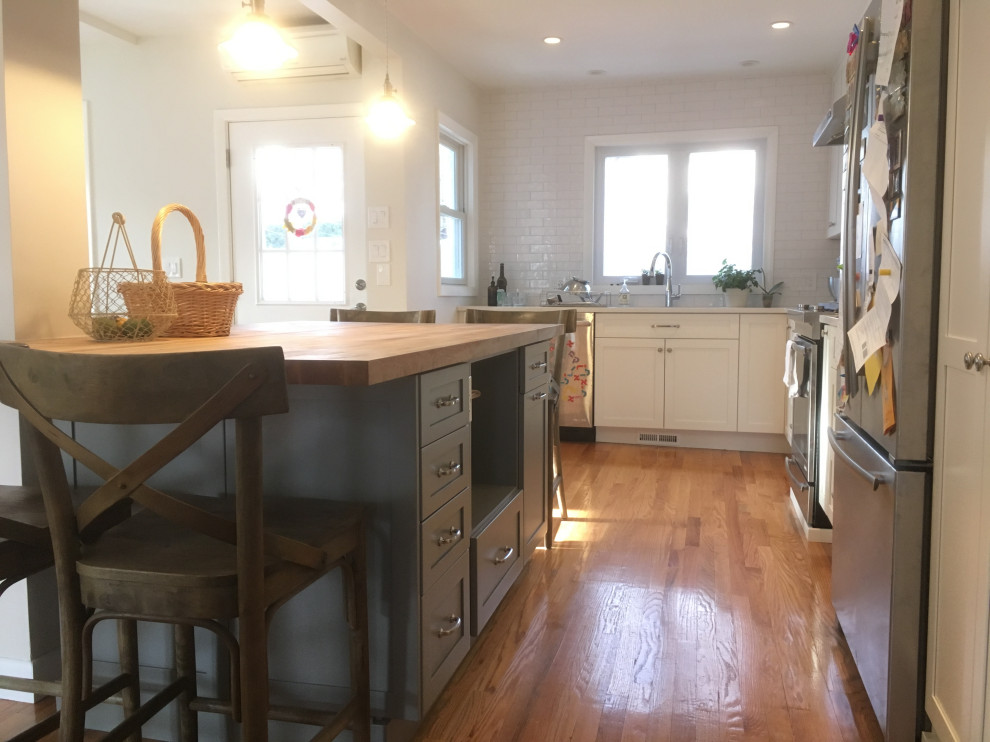 Eat-in kitchen - small farmhouse l-shaped light wood floor and beige floor eat-in kitchen idea in Boston with an undermount sink, shaker cabinets, white cabinets, quartz countertops, white backsplash, subway tile backsplash, stainless steel appliances, an island and white countertops