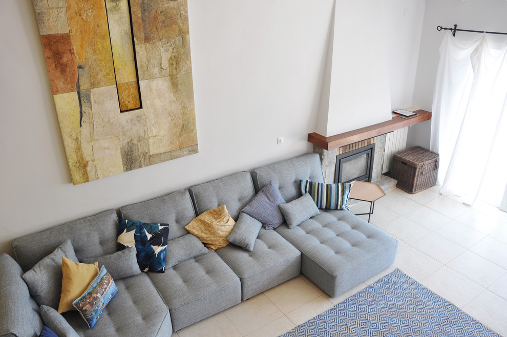 Photo of a large contemporary open concept living room in Alicante-Costa Blanca with white walls, ceramic floors, a standard fireplace, a stone fireplace surround, a wall-mounted tv and beige floor.