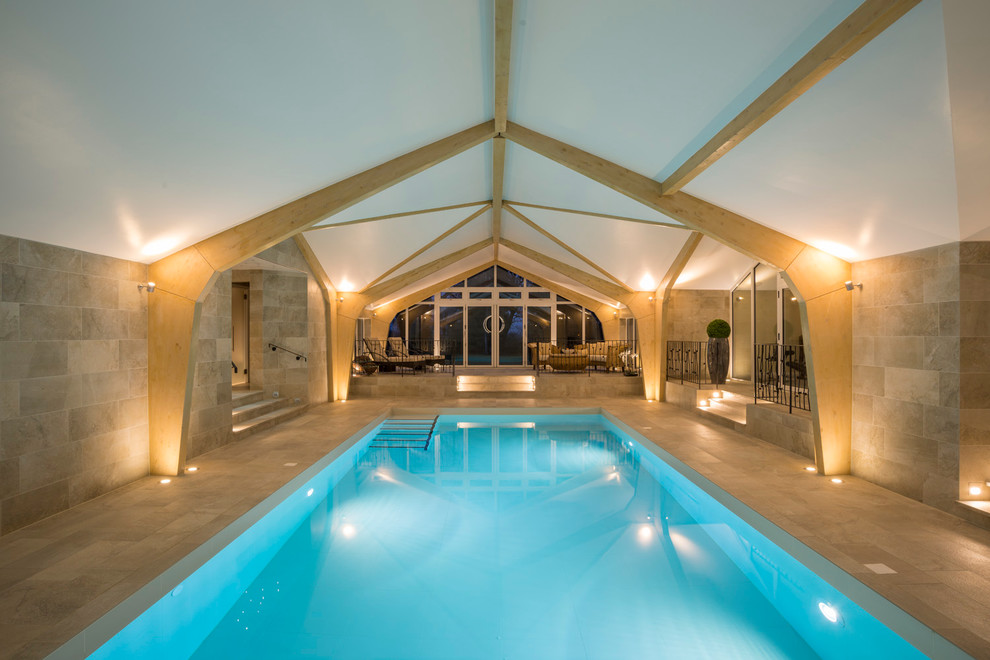 Expansive transitional indoor rectangular pool in West Midlands with natural stone pavers.