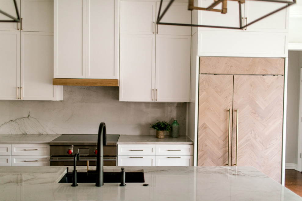 Modern inredning av ett stort beige beige kök, med en undermonterad diskho, skåp i shakerstil, gula skåp, bänkskiva i kvartsit, beige stänkskydd, stänkskydd i sten, rostfria vitvaror, mellanmörkt trägolv, en köksö och brunt golv