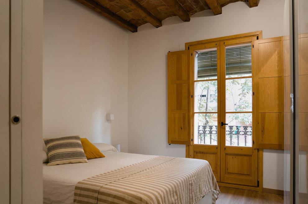 На фото: хозяйская спальня среднего размера, в белых тонах с отделкой деревом в стиле рустика с белыми стенами, паркетным полом среднего тона, коричневым полом и балками на потолке