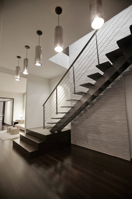 Photo of a large modern wood straight staircase in New York with open risers and cable railing.