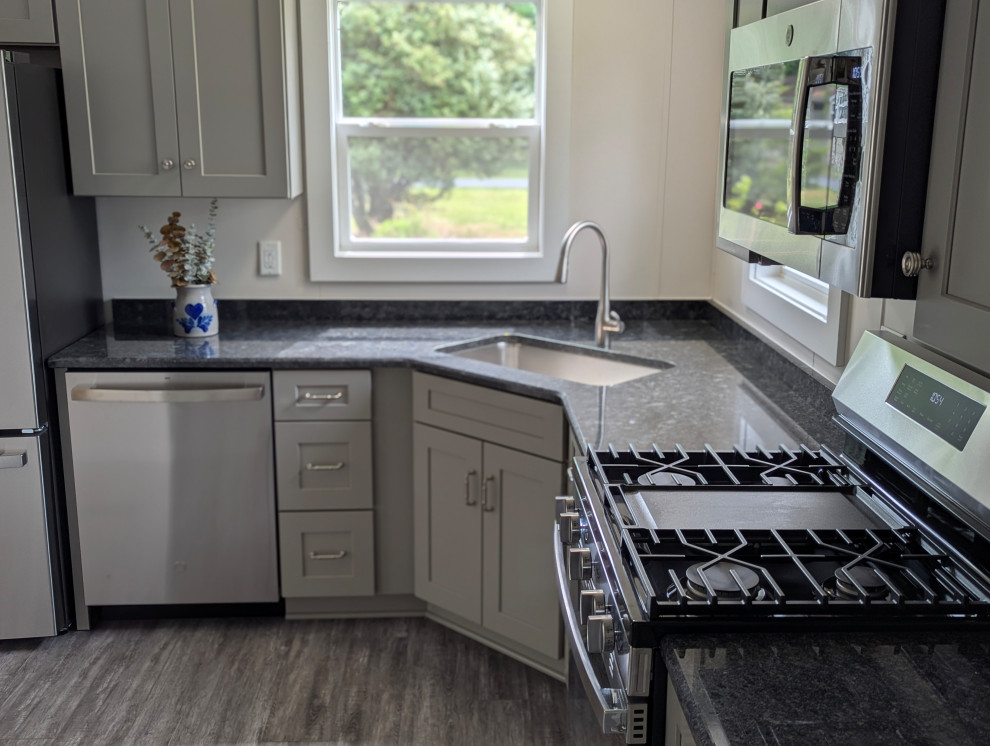 Inspiration for a small transitional l-shaped gray floor enclosed kitchen remodel with a single-bowl sink, flat-panel cabinets, gray cabinets, granite countertops, stainless steel appliances and black countertops
